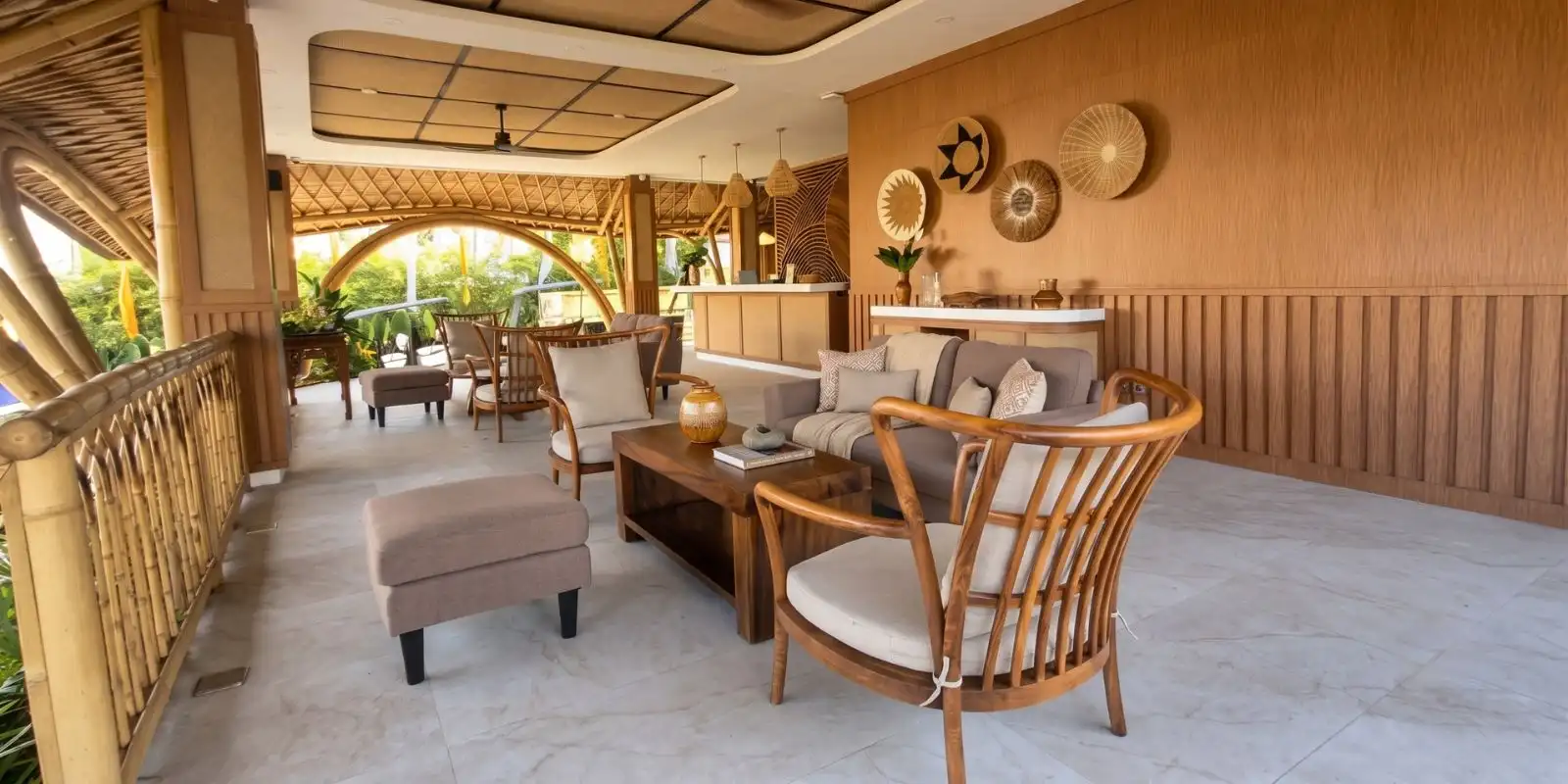 Covered tropical veranda lounge with rattan chairs, a solid teak coffee table and bamboo-arch detailing, opening off the main living area