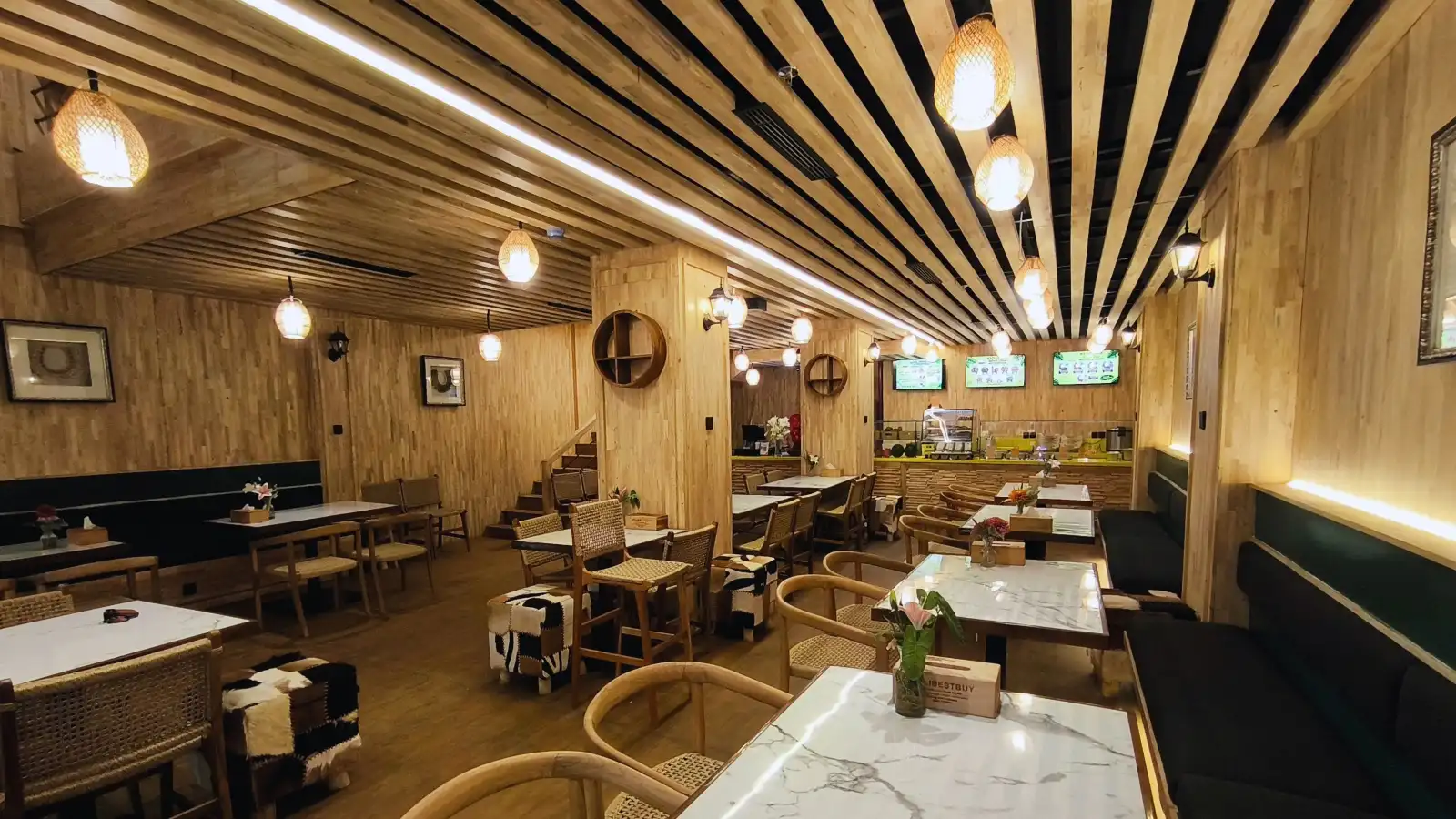Ground floor of Wak Teni nasi lemak restaurant at Discovery Mall Kuta, with rubber wood cladding, a slat ceiling, woven pendant lights and marble-look tables, designed by Bali Best Design